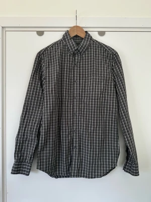 Banana Republic- Svartvit rutig skjorta, 100% bomull, storlek S - Stilren rutig långärmad slim fit skjorta från Banana Republic i storlek S. Tidlös modell med knappar  och en bröstficka framtill, och ett snyggt mönster i svart, grått, vitt och lila. Skjortan har en klassisk krage och manschetter med knappar. 100% bomull, så bra material som andas. Nypris 900:-. Mycket gott skick, som ny!