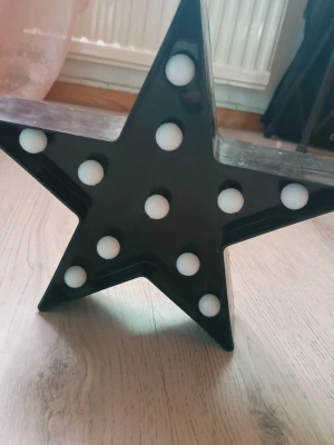 Svart stjärnlampa med LED-ljus - Cool svart dekorationslampa i form av en stjärna med vita LED-lampor. Lampan är gjord av plast och passar perfekt som mysig belysning i rummet eller till fest. Drivs med batterier och är enkel att placera tack vare sin fristående form.