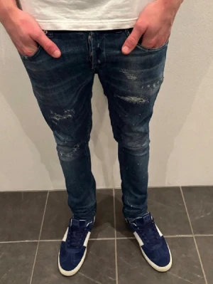 Dondup jeans  - Snygga mörkblå slim fit jeans med slitna detaljer och lätt tvättad look. Jeansen har klassisk femficksmodell och smal passform som sitter tajt längs benen. Perfekta för en trendig och avslappnad stil.