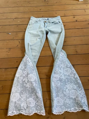 Ljusblå jeans med spets - Säljer dessa lågmidjade ljusblå jeans som är omsydda till bootcut med spets. Midjemått 36 cm och innerbenslängd 75 cm. Säljer liknande jeans i min profil💞💞