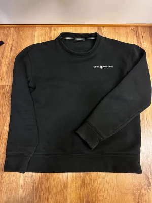 Svart sweatshirt från Sail Racing - Stilren svart sweatshirt från Sail Racing, logga på bröstet och uppe på ryggen.