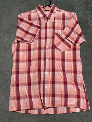 Britac Shirt – Pink Checkered – Short Sleeve – Size S - Kortärmad skjorta i rosa/röd ruta – perfekt för sommaren.  Lätt och bekväm, funkar bra till vardag eller semester.  Detaljer • Kortärmad • Rutig (rosa/röd) • Storlek S • Lätt material  📦 Skickas snabbt 💬 Skriv vid frågor