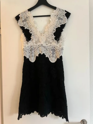 Svart och vit spetsklänning, Sandro - Snygg kort klänning i svart och vitt med vacker spetsdetalj från Sandro Paris i storlek 1 (xs)