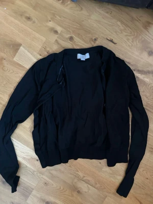 Svart basic kofta - En enkel svart kofta med långa ärmar och knäppning framtill. Perfekt att slänga över en t-shirt eller linne för en clean look. Tunn och smidig modell som passar till det mesta.