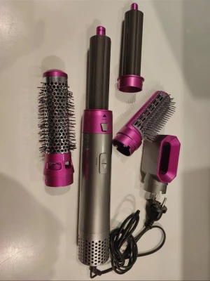 multistyler med tillbehör - Multistyler i silver och lila med flera utbytbara tillbehör: rundborste, locktillbehör, utjämningsborste och fönmunstycke. Perfekt för att styla håret på olika sätt med ett och samma verktyg. Sladd medföljer.