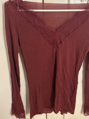 SLUTSÅLD Vinröd långärmad topp med spets . - Vinröd långärmad topp med v-ringning och spetsdetaljer vid halsringningen och ärmsluten. Tunn och mjuk, perfekt för lager på lager eller som den är. Snygg och enkel att matcha till olika outfits.INTE MIN BILD MEN SER EXAKT LIKA DAN UT ❤️❤️