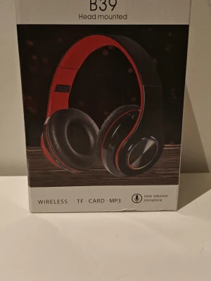 B39 trådlösa hörlurar svart oöppnad. - Snygga trådlösa over-ear hörlurar i svart färg med vadderade kåpor och justerbart huvudband. Stöd för TF-kort, MP3 och Bluetooth 5.0. Inbyggd mikrofon med brusreducering och lång batteritid. Perfekt för musik och samtal. Gaming hörlurar har MP3 , RADIO , och laddning USB-C kabeln med i boxen. Den lyser som på paketets bild med alla färger när den är påslagen. 