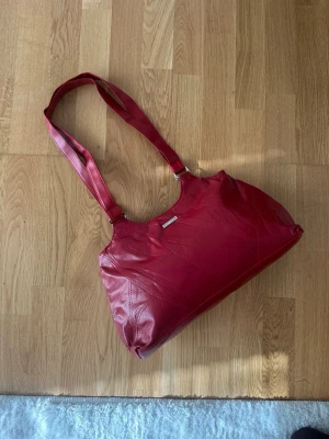 Vintage STEFANO Handväska i Äkta Läder – Cherry Red - Säljer en otroligt snygg vintageväska från Stefano i mjukt, äkta läder. Väskan har en helt fantastisk djupröd nyans (Cherry Red) som är en av säsongens absolut trendigaste färger! Detaljer: • Material: 100% Äkta läder. Mjukt, slitstarkt och med en naturlig lyster som bara riktigt skinn har. • Design: Stilrent patchwork-mönster med dekorativa stickningar. En klassisk axelremsmodell som sitter perfekt under armen. • Skick: Mycket fint vintage-skick! Lädret är välvårdat och har inga stora skador.