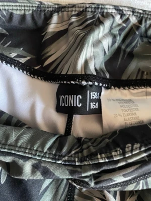 Mönstrade leggings från ICONIC - Snygga leggings från ICONIC med grön-svart tropiskt bladmönster. Tillverkade i 80% polyester och 20% elastan för en stretchig och bekväm passform. Perfekta för dig som vill ha något unikt och trendigt i garderoben.