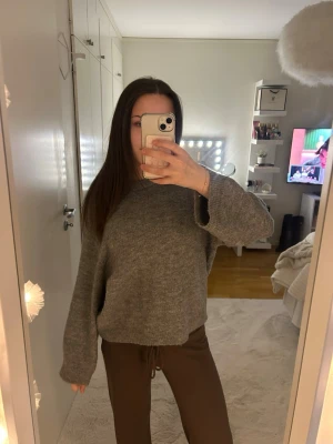 Grå oversized stickad tröja - Mysig grå stickad tröja med avslappnad, oversized passform och rund hals. Tröjan har långa ärmar och ribbade muddar vid ärmslut och nederkant. Perfekt för lager på lager och chill dagar.