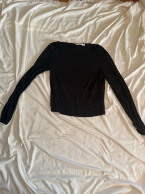 Svart långärmad topp - En enkel och stilren svart långärmad topp med rund hals. Toppen har en tight passform och är perfekt att matcha med både jeans och kjol. Materialet känns mjukt och stretchigt, vilket gör den bekväm att bära hela dagen.