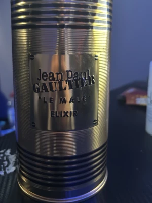 Jean Paul Gaultier Le Male Elixir - Säljer en Jean Paul Gaultier Le Male Elixir parfym i en unik guldfärgad flaska formad som en manlig torso. Flaskan har en metallisk finish och levereras i en matchande guldfärgad burk med märkets logga. Perfekt för dig som gillar exklusiva och iögonfallande dofter.