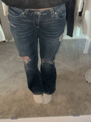Mörkblå bootcut jeans med slitningar - Säljer jeans med slitningar! Säljer för att jag inte använder dem. Endast använd några få gånger! Slitningarna är ursprungliga. 🩷 är 170cm och sitter bra i längden. Lågmidjade. Snygga detaljer på baksidan💋💋skriv privat för mer bilder eller info🫶🏼