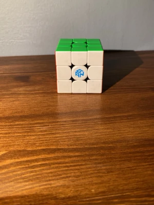 GAN Rubiks kub 3x3 - Säljer en klassisk 3x3 Rubiks kub från GAN med vita, gröna och orange sidor. Kuben har en modern design med rundade hörn och GAN-logga i mitten. Perfekt för dig som gillar hjärngympa och speedcubing.