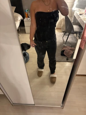 Svarta raka jeans med låg midja - Säljer ett par svarta jeans med rak passform och hög midja. Jeansen har klassisk femficksdesign och silverfärgade knappar. Perfekta för en clean och stilren look. Materialet är denim i bomull.