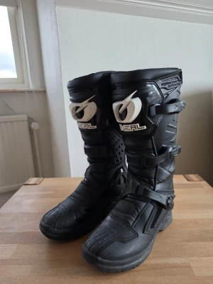 Svarta crossstövlar från O'Neal - Säljer ett par svarta crossstövlar från O'Neal med robust design och höga skaft. Stövlarna har justerbara spännen och förstärkta partier för extra skydd. Tillverkade i slitstarkt syntetmaterial och passar perfekt för motocross eller enduro.