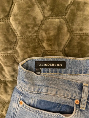 Blå jeans från J.Lindeberg - Säljer ett par klassiska blå jeans från J.Lindeberg. Jeansen har fem fickor, snygga kopparfärgade nitar och en ljus tvätt. Perfekta för dig som gillar stilrena och tidlösa plagg. Passar till det mesta och har en skön passform. Aldrig använda