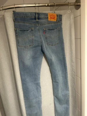 Levi's ljusblå skinny jeans - Säljer ett par klassiska ljusblå skinny jeans från Levi's med fem fickor och ikonisk läderpatch bak i midjan. Jeansen har normalhög midja, smal passform och är tillverkade i mjukt denimtyg. Perfekta för en avslappnad och trendig look.