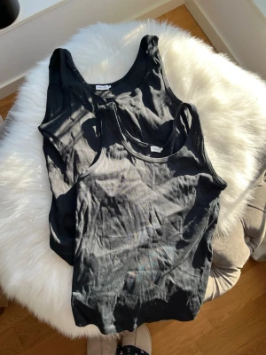 2 Filippa K linnen - Två svarta linnetoppar med klassisk rund halsringning. Perfekta att styla lager på lager eller bära som de är. Tillverkade i mjuk bomull för en bekväm känsla hela dagen. Från Filippa K.