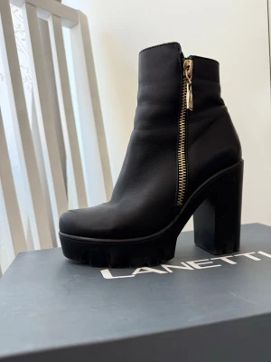 Svarta stövletter med chunky klack - Vinterkängor i skinn med klack och grov sula. Storlek 37. Använda en säsong och i mycket fint skick.  De är mycket bekväma att gå i och passar perfekt för vinter/höst dagar. Praktisk dragkedja och en dekorativ guld dragkedja på sidan – ger en snygg och unik touch.  Stabila, varma och stilrena – enkla att matcha till både vardag och mer uppklädda outfits.