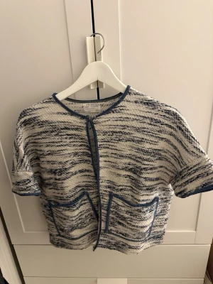 Kortärmad kofta i blåvitt mönster - Kortärmad kofta från Zara  i blåvitt melerat mönster. Koftan har två framfickor, rund halsringning och blå kantband. Den är från Zara barn i storlek 140 men passar storlek XS/S