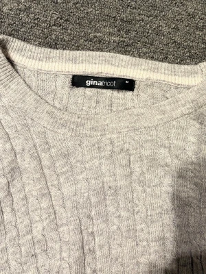 Ljusgrå Tröja - Ljusgrå kabelstickad tröja från Gina Tricot med rund halsringning och långa ärmar. Tröjan har ett klassiskt flätmönster och ribbade muddar vid ärmslut och nederkant. Perfekt att matcha med jeans eller mjukisbyxor. Sälja eftersom den är för stor för mig 💗