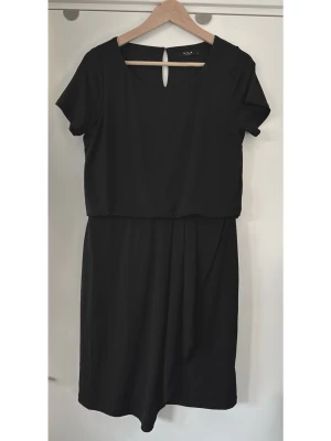 Svart draperad klänning från Vila, storlek M - Superfin svart klänning från VILA i storlek M. Stilren modell med korta ärmar och en rund halsringning med en liten öppning och knapp baktill. Praktisk elastisk midja för bästa passform, med elegant omlottliknande drapering på kjolen framtill. Mjukt och följsamt material i modell som är smickrande på alla kroppsformer. Superfin, men tyvärr för liten för mig nu. Mycket gott skick, som ny.   (Skickas helst, men kan även hämtas i Stockholm vid behov)