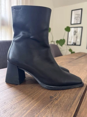 Svarta stövletter från Vagabond - Hedda - Snygga svarta stövletter från Vagabond i mjukt skinn. Modellen har fyrkantig tå, bred klack och dragkedja på insidan. 70 mm klack! Använda 2 ggr så de är i nyskick!