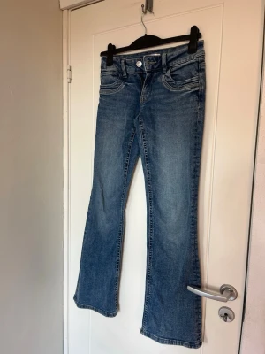 Blå lågmidjade bootcut jeans  - Säljer ett par blå lågmidjade bootcut jeans. Dragkedjegylf och är tillverkade i denim. Perfekta för en avslappnad och trendig look. Storlek 164 men passar xs. Endast använda en gång. Nypris 359kr. 