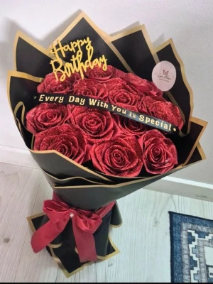 Bukett med röda glittriga rosor - Snygg bukett med konstgjorda röda rosor dekorerade med glitter, inslagna i svart och guld papper samt en röd rosett. Toppen har en 'Happy Birthday'-skylt och ett band med texten 'Every Day With You is Special'. Perfekt som present.
