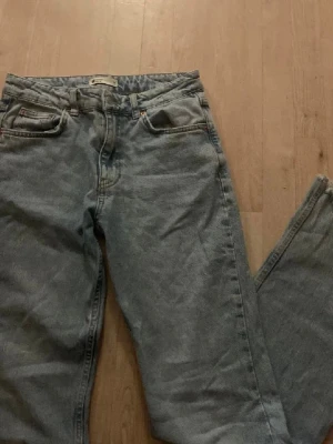 Ljusblå bootcut jeans  - Säljer ett par ljusblå jeans och rå, fransig kant längst ner på benen. Klassisk femficksmodell i denim med dragkedja och knapp. Perfekta för en avslappnad och trendig look.