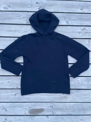 Svart hoodie från H&M - En stilren svart hoodie från H&M med klassisk huva och ribbade muddar vid ärmslut och nederkant. Perfekt för en avslappnad look och enkel att matcha med andra plagg. Ett bra klädesplagg helt enkelt, fråga vid intresse!!