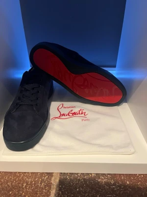 Mörkblå sneakers från Christian Louboutin - Snygga mörkblå sneakers i mocka från Christian Louboutin med klassisk röd sula och svarta skosnören. Vara inte blyga och skicka gärna vid intresse går med på det mesta