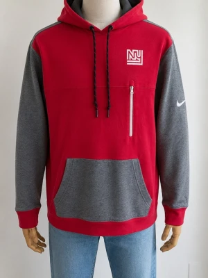 Nike NFL New York Giants Hoodie XL – Team Apparel 🔥 - Snygg hoodie från Nike i rött och grått med vit NY-logga på bröstet och vit Nike Swoosh på ärmen. Huva med dragsko, magficka och en vit dragkedjeficka på bröstet. Perfekt för en sportig och avslappnad stil.