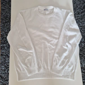 Vit stickad tröja från Zara  - Klassisk vit stickad tröja från Zara i storlek XL, passar L/M. Tröjan har rund halsringning, ribbade muddar och är långärmad. Perfekt för lager-på-lager och enkel att matcha med olika outfits.
