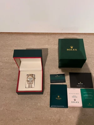 Role Klocka  - Exklusiv Role klocka i guld med silverfärgad urtavla och gnistrande stenar på både boett och armband. Klockan levereras i originalbox med tillhörande certifikat och dokumentation. En riktigt lyxig accessoar som sticker ut och ger en elegant känsla.