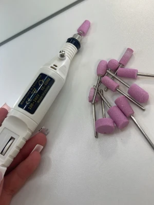 Elektrisk nagelfil ink filar  - Elektrisk nagelfil i vitt med flera utbytbara rosa sliphuvuden. Perfekt för manikyr och pedikyr, har en enkel on/off-knapp och ansluts med sladd. Sliphuvudena är cylinderformade och tillverkade i slipmaterial med metallfäste. Funkar som den ska och jätte stark!