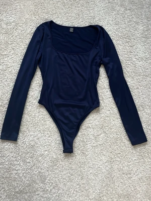 Mörkblå långärmad body - Jättefin body i storlek M, dock lite liten i storlek! Säljer då den är i fel storlek endast använd och tvättad 2 gånger så i mycket fint skick!! OBS färgen är mest rätt på bild 1