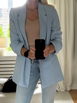 Ljusblå viscose kavaj Ny stl XS - En ljusblå kavaj från H&M med en klassisk design. Ärmarna är långa och har en rak passform. Stl XS, passar en small bra. Viscose 95% supermjuk och har ett fint fall. Ej använd, är i nyskick. Nypris 399kr