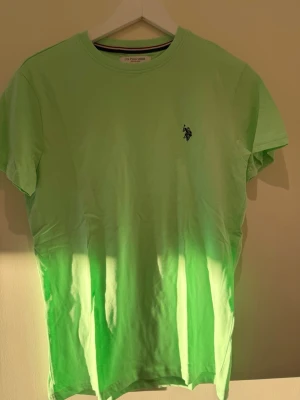 Ljusgrön t-shirt från U.S. Polo Assn - Fräsch ljusgrön t-shirt från U.S. Polo Assn med klassisk rund hals och liten broderad logga på bröstet. Tillverkad i mjuk bomull och har en enkel, stilren design som passar perfekt till jeans eller shorts.