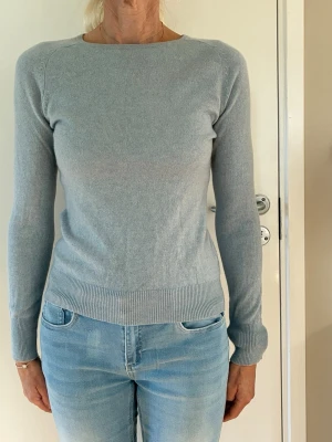 Cashmere tröja ljusblå stl S - Klassisk stickad tröja i 100% cashmere. Ljusblå. Tröja med långa ärmar och rund halsringning. Ribbstickade muddar i ärmslut och nederkant. Raglanärmar. Stl S. H&M Premium. Använd ett fåtal ggr, är i mkt bra skick, inga defekter, inga noppor. Nypris 999kr.