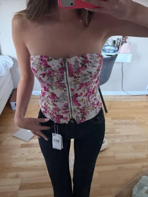 Blommig korsett topp - Super snygg och sommrig topp🌸högt pris pga att jag är osäker på om jag vill sälja. Den är i storlek M men passar även mig som vanligtvis har xs/s och B/C i kupa