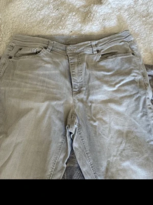 Ljusgrå jeans från Raffaello Rossi - Säljer ett par ljusgrå jeans från Raffaello Rossi. Klassisk femficksmodell med dragkedja och knapp framtill. Jeansen har raka ben och är tillverkade i mjukt denimtyg som ger en avslappnad look. Perfekta för dig som gillar stilrena och neutrala färger. Det har en liten fläck som man ser på sista bilden 