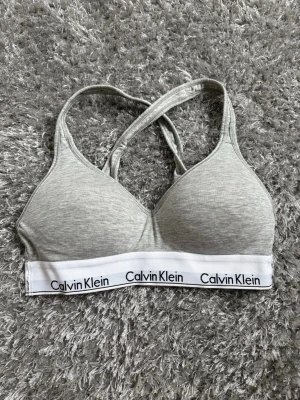 Grå sport-bh från Calvin Klein - Snygg grå sport-bh från Calvin Klein med vadderade kupor och korsade axelband i ryggen. Pris går alltid att diskutera!