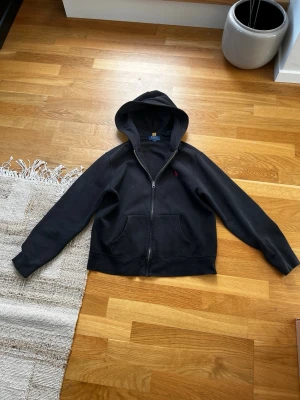 Svart hoodie med dragkedja från Polo Ralph Lauren - PRIS KAN DISKUTERAS!Svart hoodie med dragkedja från Polo Ralph Lauren. Klassisk design med huva. Perfekt för en chill och stilren look.