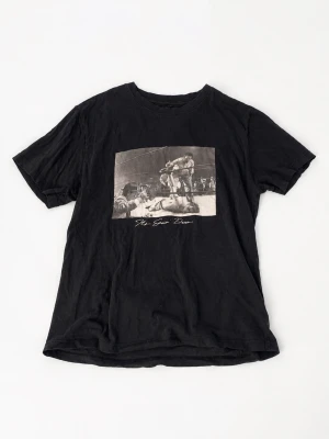 Svart t-shirt med boxningsmotiv - Cool svart t-shirt med korta ärmar och tryck framtill som visar en klassisk boxningsscen. T-shirten har en avslappnad passform och är tillverkad i mjuk bomull. Perfekt för dig som gillar sportiga och stilrena plagg. Sparsamt använd 