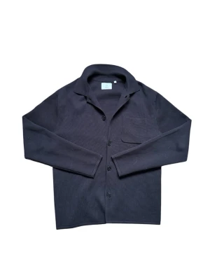 Bläck overshirt - Stilren svart overshirt från Black med klassisk krage, knäppning framtill och en bröstficka. Tillverkad i ett mjukt, stickat material som ger en avslappnad men ändå uppklädd look. Perfekt att bära över en t-shirt eller skjorta.