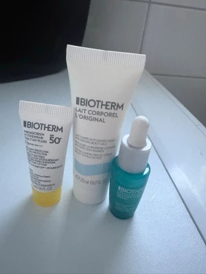 Biotherm miniset hudvård - Ett miniset från Biotherm med tre produkter: en vit solkräm med SPF 50, en vit kroppslotion och ett blått serum med pipett. Perfekt för dig som vill testa olika hudvårdsprodukter från Biotherm i mindre förpackningar.