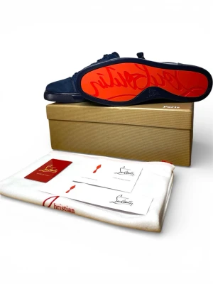 Blå sneakers från Christian Louboutin - Snygga blå sneakers från Christian Louboutin i mocka med klassisk röd sula och guldfärgad logga på insidan. Skorna har rund tå, matchande blå skosnören och diskreta sömdetaljer. tidy och exklusiv design parkopplad med märkets ikoniska signatur.