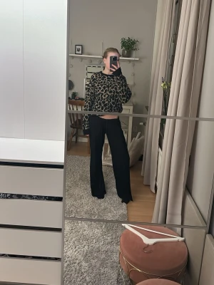 Leopardmönstrad stickad tröja - Cool stickad tröja med leopardmönster i svart och beige. Tröjan har en avslappnad passform, rund hals och långa ärmar med ribbade muddar. Perfekt för dig som gillar att sticka ut och vill ha något mjukt och trendigt i garderoben.